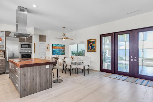 kitchen featuring french doors, wooden counters, built in appliances, a kitchen island, and island exhaust hood