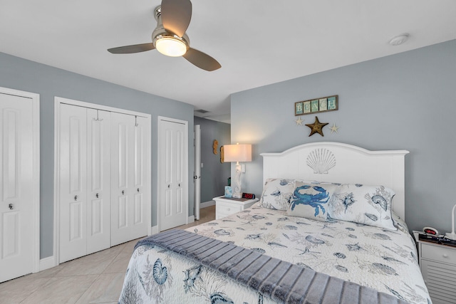 tiled bedroom featuring ceiling fan and multiple closets