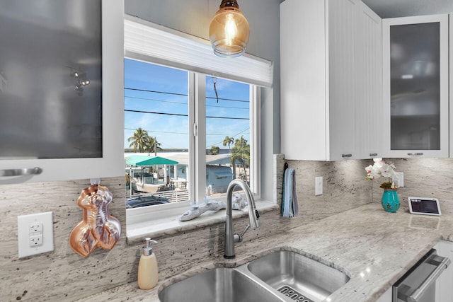 kitchen featuring sink, backsplash, white cabinets, and light stone counters