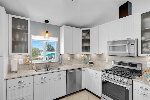 kitchen featuring sink, white cabinets, hanging light fixtures, stainless steel appliances, and light stone countertops