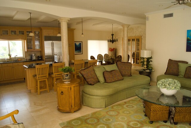 living room featuring decorative columns, ornamental molding, sink, and ceiling fan