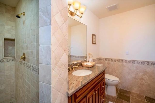 bathroom featuring vanity, tiled shower, tile walls, and toilet