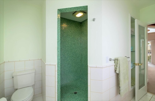 bathroom featuring toilet, tile patterned flooring, and tile walls