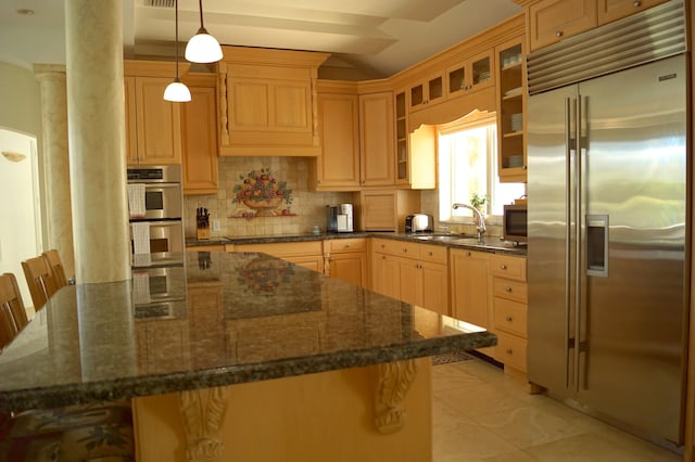 kitchen featuring sink, a breakfast bar, appliances with stainless steel finishes, dark stone countertops, and hanging light fixtures