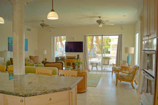 kitchen featuring hanging light fixtures, light stone countertops, stainless steel double oven, and ornate columns