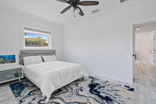 bedroom with ceiling fan, ornamental molding, and wood-type flooring