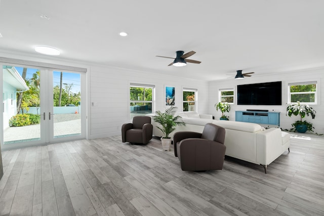 living room with ceiling fan, a wealth of natural light, light wood-type flooring, and french doors