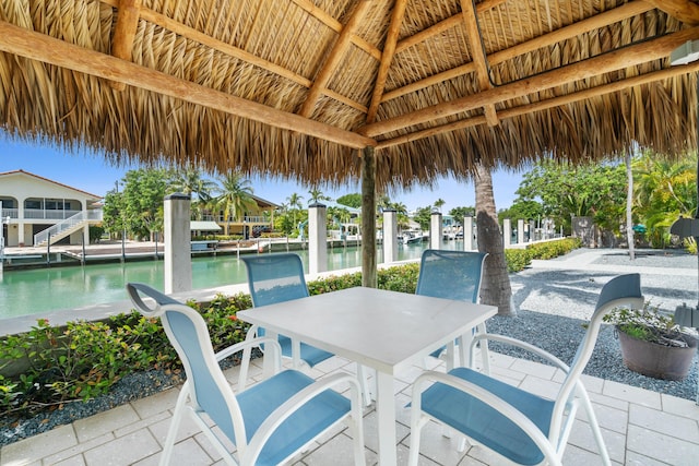 view of patio with a gazebo, a water view, and a boat dock