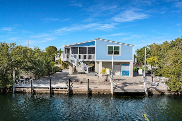 back of property with a water view, a patio area, and a sunroom