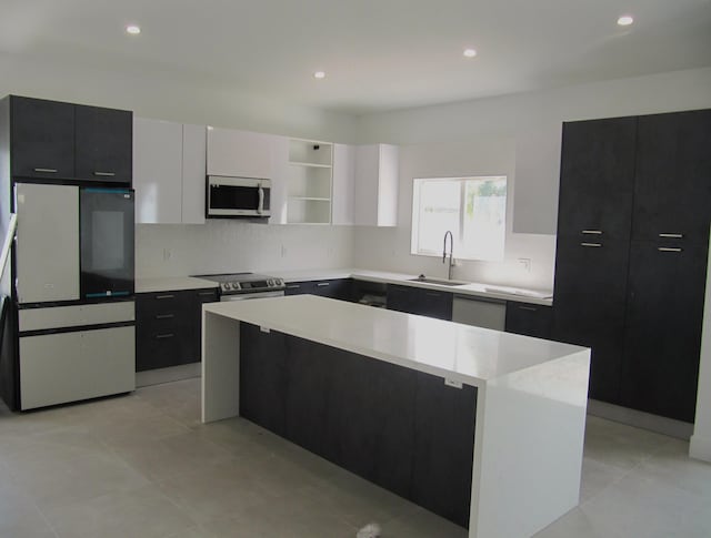 kitchen featuring sink, stainless steel appliances, a center island, tasteful backsplash, and white cabinets