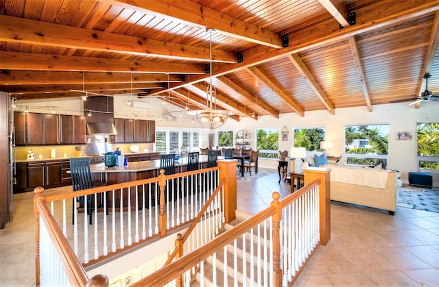 interior space featuring vaulted ceiling with beams, light tile patterned floors, ceiling fan with notable chandelier, and wooden ceiling