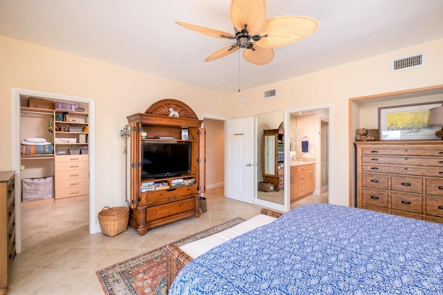 tiled bedroom with connected bathroom, a spacious closet, a closet, and ceiling fan