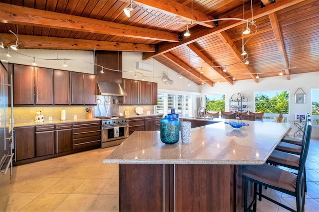 kitchen with wall chimney range hood, stainless steel stove, and a spacious island