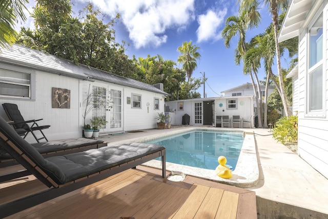 outdoor pool with a deck, french doors, a patio area, and an outdoor structure