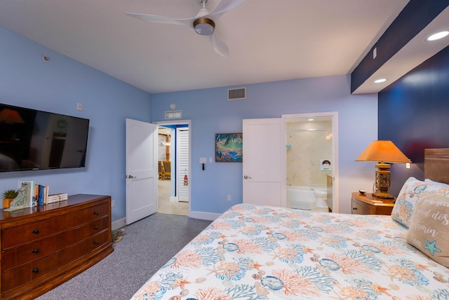 bedroom with ceiling fan, dark carpet, and ensuite bath