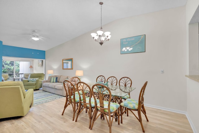 dining room with lofted ceiling, ceiling fan with notable chandelier, and light wood-type flooring