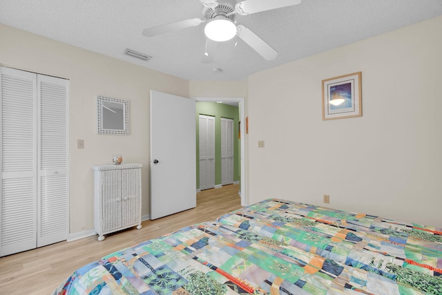 bedroom with ceiling fan, a textured ceiling, light wood-type flooring, and a closet