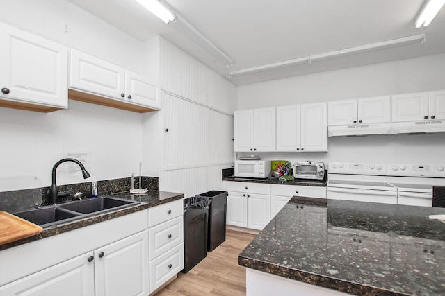 kitchen with sink, white appliances, white cabinetry, dark stone counters, and light wood-type flooring