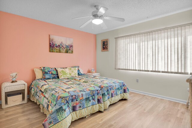 bedroom with ceiling fan, light hardwood / wood-style floors, and a textured ceiling