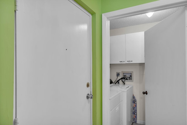 washroom with cabinets, washing machine and clothes dryer, and a textured ceiling