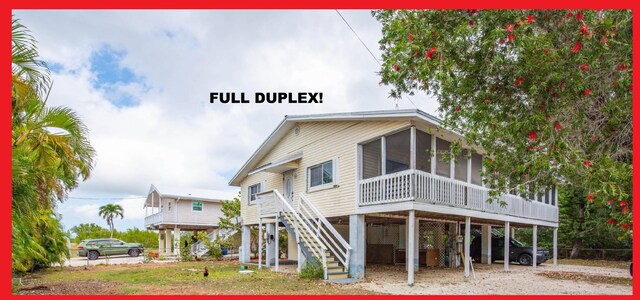 view of front of property with a sunroom, stairs, and a carport