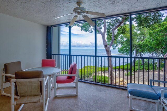 sunroom / solarium featuring ceiling fan and a water view