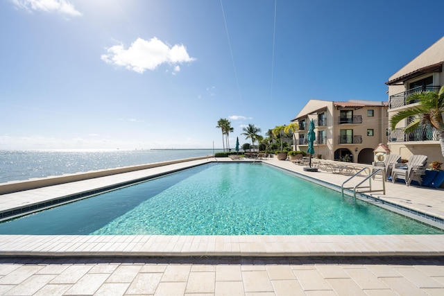 view of swimming pool with a water view and a patio area