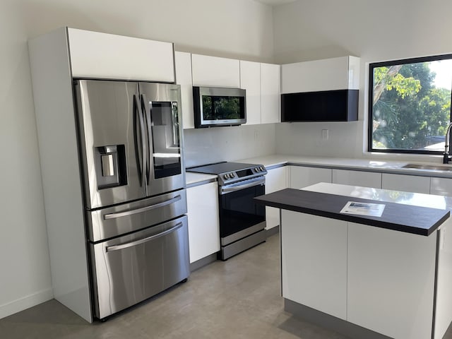 kitchen featuring tasteful backsplash, white cabinetry, appliances with stainless steel finishes, and sink