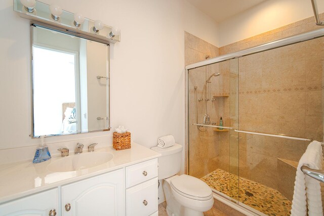 bathroom with vanity, a shower with shower door, and toilet