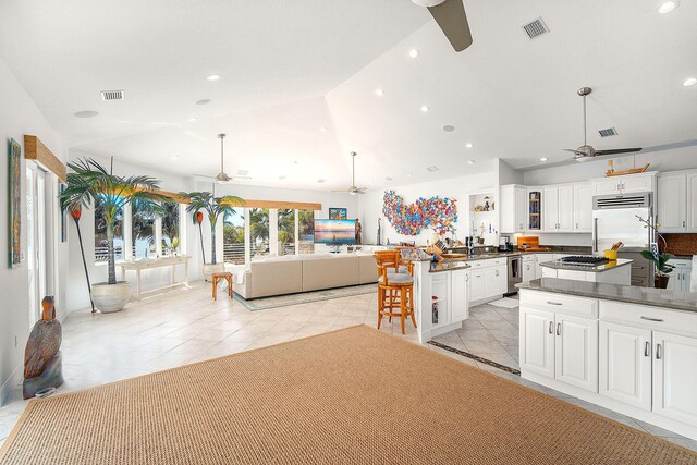 kitchen with lofted ceiling, white cabinets, decorative light fixtures, and ceiling fan