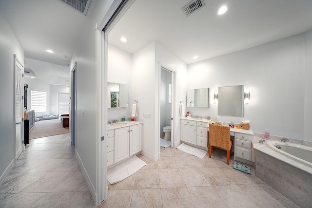 bathroom with tile patterned flooring, vanity, tiled bath, and toilet