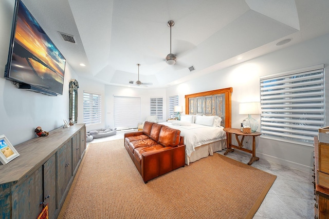 bedroom featuring light tile patterned flooring, ceiling fan, and a tray ceiling