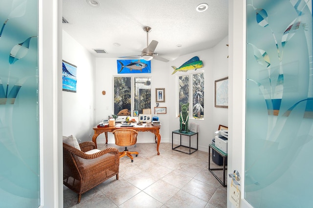 tiled office space featuring ceiling fan and a textured ceiling