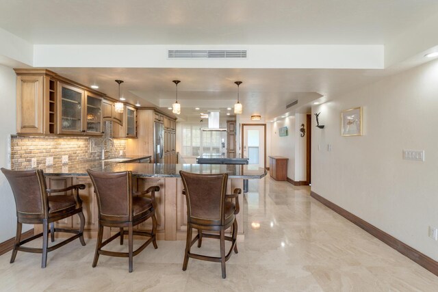 kitchen with pendant lighting, sink, dark stone countertops, decorative backsplash, and kitchen peninsula