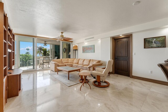 living room with ceiling fan, a textured ceiling, and a wall of windows