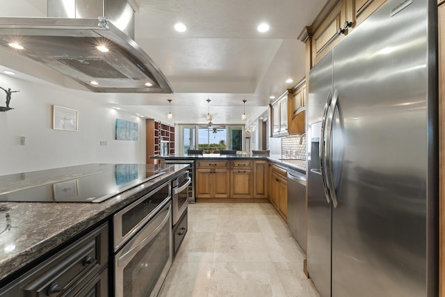 kitchen with decorative light fixtures, dark stone countertops, island exhaust hood, kitchen peninsula, and stainless steel appliances