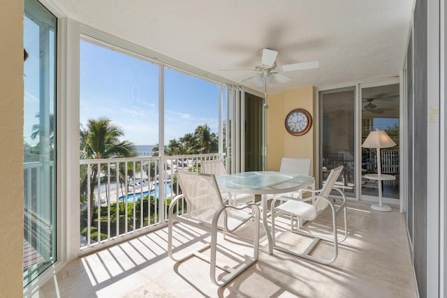 sunroom / solarium with ceiling fan and a water view