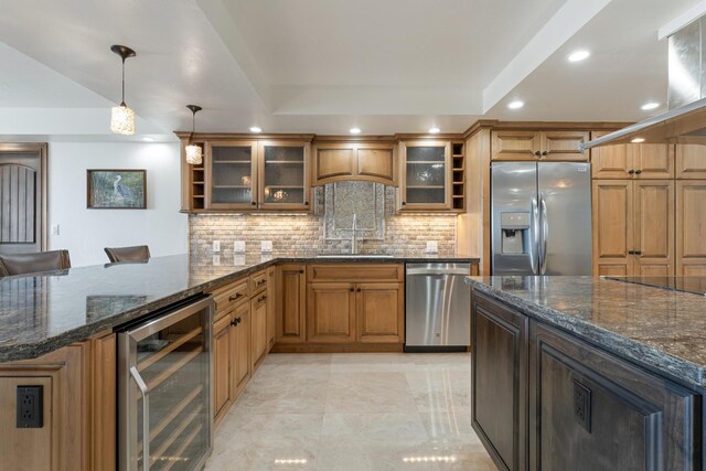 kitchen featuring sink, hanging light fixtures, dark stone countertops, stainless steel appliances, and beverage cooler