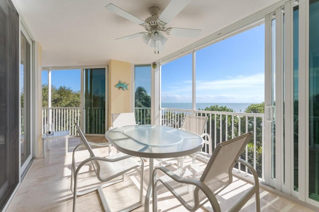 sunroom with ceiling fan and a water view