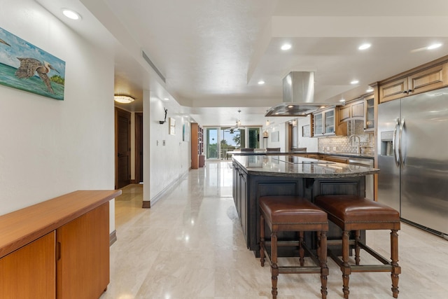 kitchen featuring a large island, a breakfast bar, backsplash, island range hood, and stainless steel fridge with ice dispenser