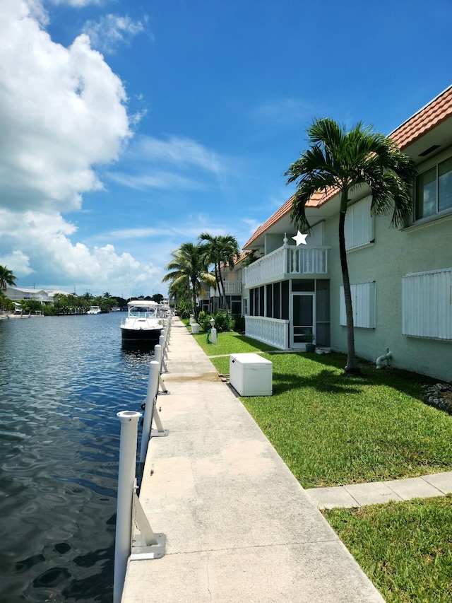 view of dock with a lawn and a water view