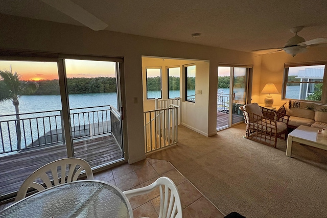 sunroom / solarium with a water view and ceiling fan