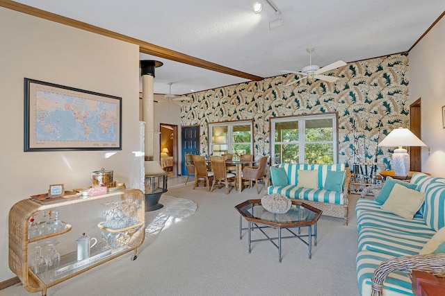 living room featuring a textured ceiling, ornamental molding, carpet flooring, ceiling fan, and beam ceiling