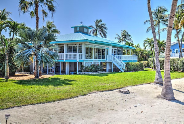 back of property featuring a sunroom and a lawn