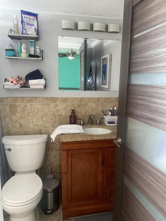 bathroom with vanity, tile walls, and toilet