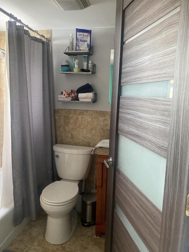 bathroom featuring shower / bathtub combination with curtain, tile patterned floors, toilet, and tile walls