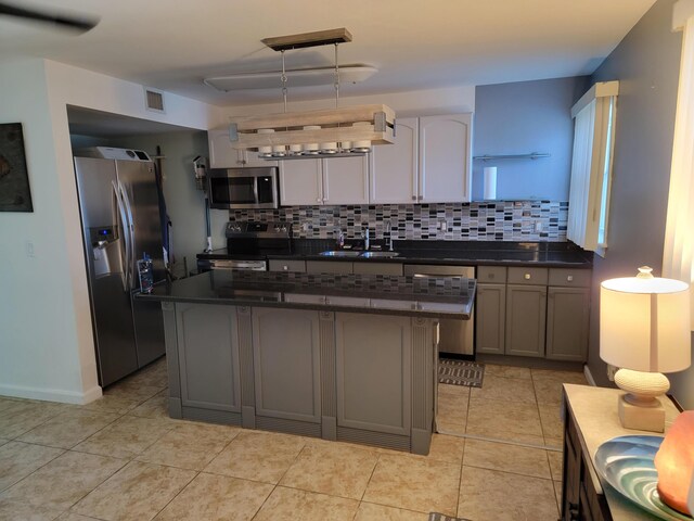 kitchen with a kitchen island, pendant lighting, sink, gray cabinetry, and stainless steel appliances