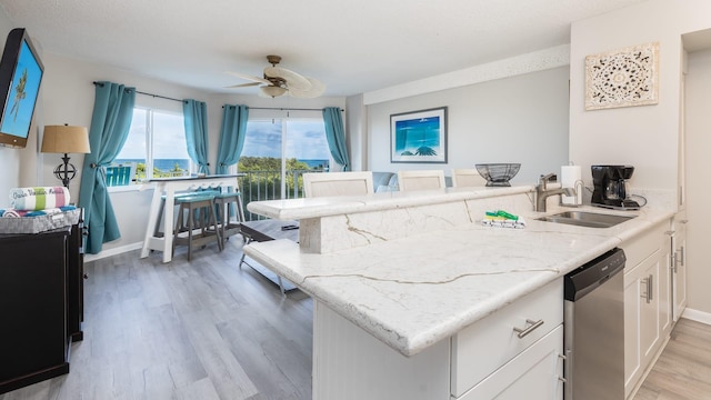 kitchen featuring sink, white cabinetry, light hardwood / wood-style flooring, kitchen peninsula, and dishwasher