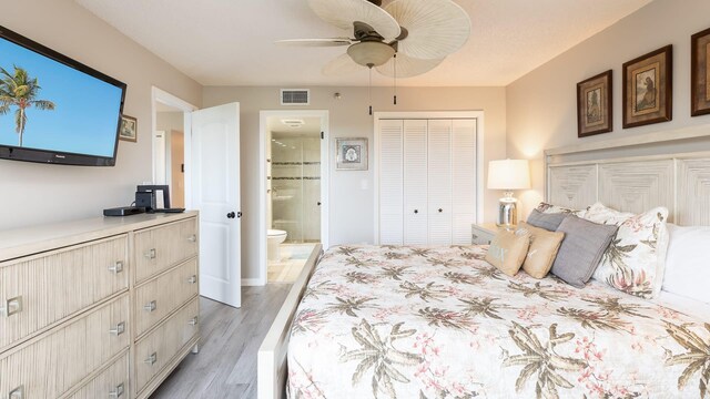 bedroom featuring ceiling fan, a closet, connected bathroom, and light hardwood / wood-style flooring