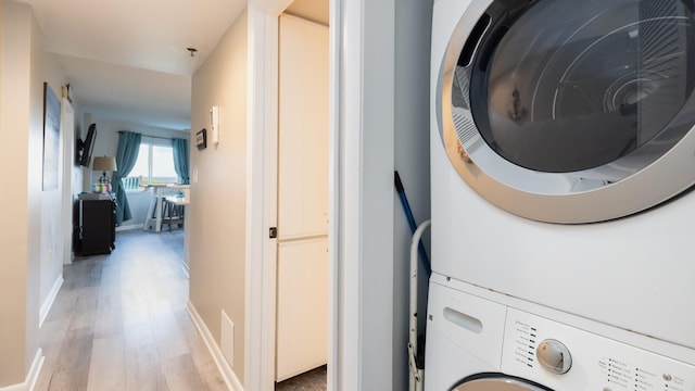 laundry area with stacked washer and dryer and wood-type flooring